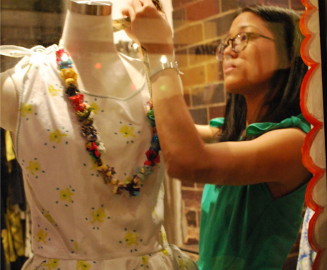 A shop assistant in a bright green dress fixes a mannequin at the EP by Easton Pearson store launch.