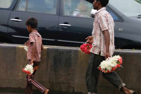 A man and boy sell flowers by the roadside. 