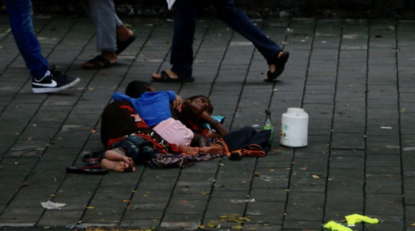 A woman and her child sleep on the pavement in the business district.
