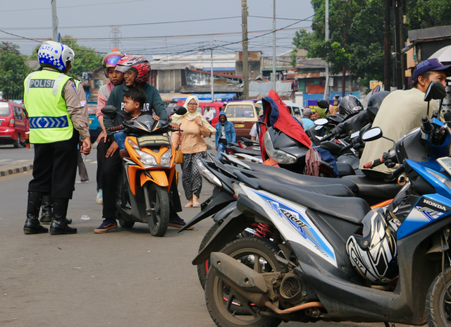 Polisi pulling over a family on a motorcycle in Depok.