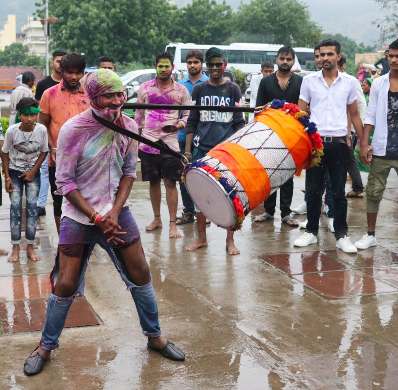 A man swings a drum around his neck.